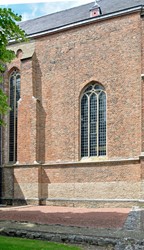 <p>Gedeelte van de zuidgevel van het schip, ter hoogte van de voormalige doopkapel. De zichtbare steunbeer behoorde bij de doopkapel, direct links van het venster was oorspronkelijk nog een steunbeer aangebracht om de tegendruk van het achterliggende gewelf van het schip op te vangen. Na de sloop van de doopkapel is daarvan het gedeelte buiten de kerkmuur weggehakt en werd de linker steunbeer een stuk verbreed in een symmetrische vorm. </p>
